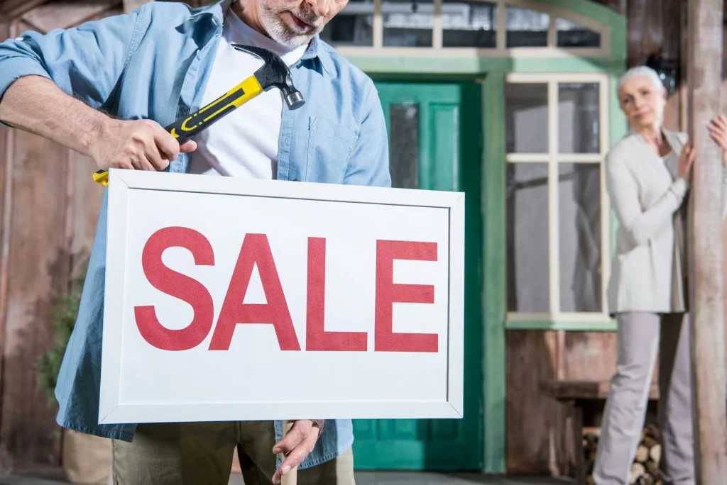 close up of sale sign senior couple selling their house