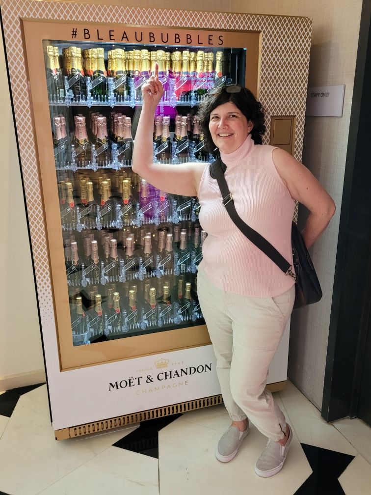 Shawna standing next to a Champagne vending machine